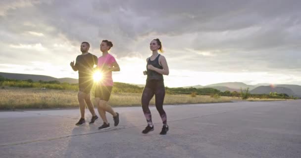 Multiethnische Gruppe von Athleten, die gemeinsam auf einer panoramischen Landstraße laufen. Vielfältiges Jogger-Team beim Morgentraining. — Stockvideo