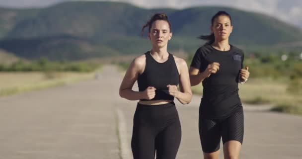 Крупним планом дві жінки в чорному спортивному одязі бігають в сонячний день — стокове відео