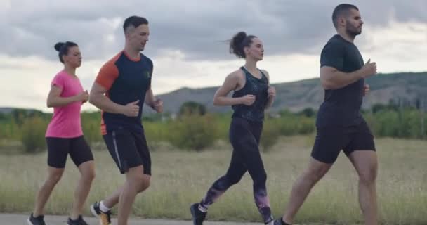 Multiethnische Gruppe von Athleten, die gemeinsam auf einer panoramischen Landstraße laufen. Vielfältiges Jogger-Team beim Morgentraining. — Stockvideo