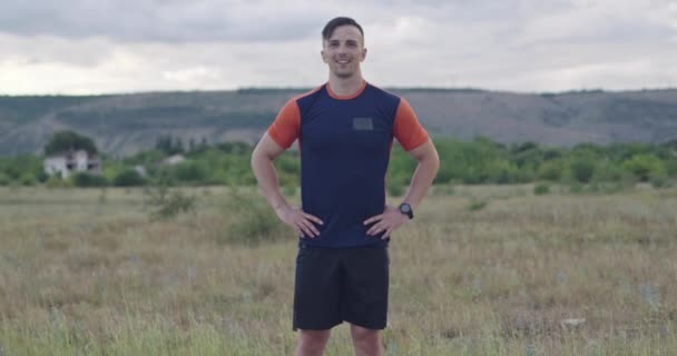 Портрет решительного парня, стоящего на дороге в спортивной одежде и готовящегося к утренней пробежке — стоковое видео