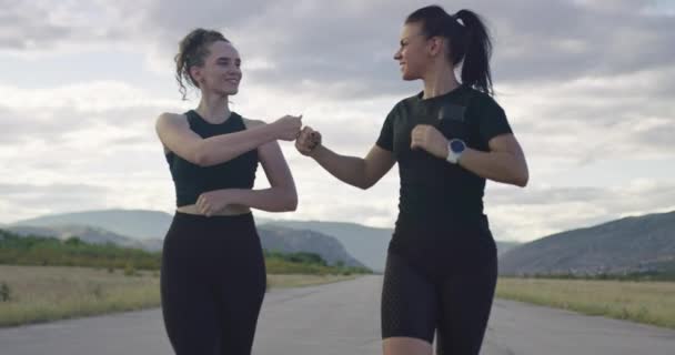 Closeup of two women in black sportswear running on a sunny day — Vídeos de Stock