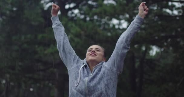 Ein Athlet, der die Hände in die Luft reckt und sich nach dem Laufen an einem regnerischen Tag frei fühlt — Stockvideo