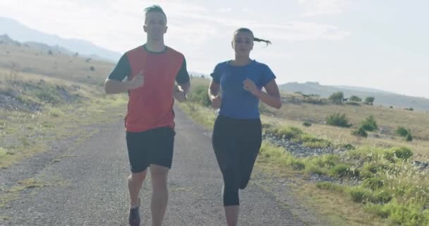 Rastreamento tiro em câmera lenta de casal esportivo correndo ao ar livre pela manhã, experiência de corrida de trilha na natureza. Conceito de estilo de vida saudável. — Vídeo de Stock