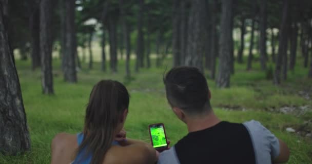 Happy man and woman use the phone smiling after a morning run and look for a new running route — Video