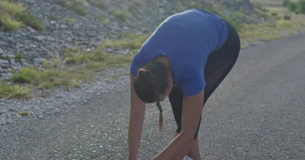 Kobieta sportowiec robi ćwiczenia rozciągające w przyrodzie. Biegaczka rozciągająca mięśnie ciała — Wideo stockowe