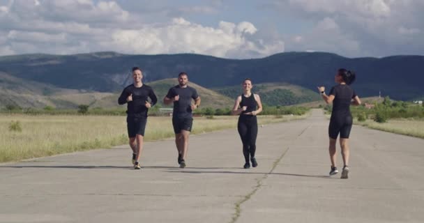 Multietnická skupina sportovců běžících společně na panoramatické venkovské silnici. Různorodý tým běžců na ranním tréninku. — Stock video