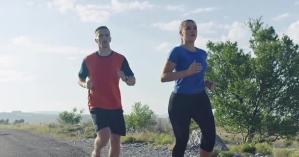 朝に屋外でスポーツカップルジョギングのスローモーションショットを追跡し、自然界でのトレイルランニング体験。健康的なライフスタイルのコンセプト. — ストック動画