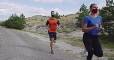 Bir salgın sırasında yolda koşan tıbbi maskeli genç bir çift. Spor ve koronavirüs. Covid 19.