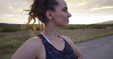 Woman takes a break from running at sunset