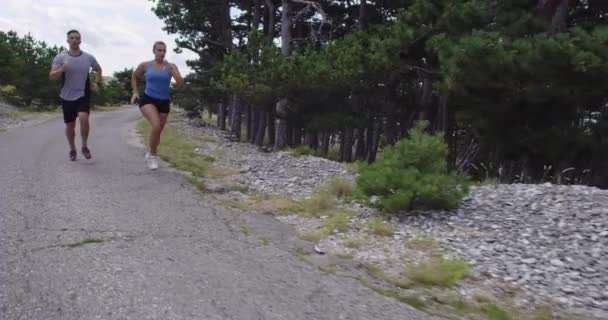 Seguimiento de la toma de cámara lenta de la pareja deportiva corriendo al aire libre en la mañana, la experiencia de trail running en la naturaleza. concepto de estilo de vida saludable. — Vídeos de Stock