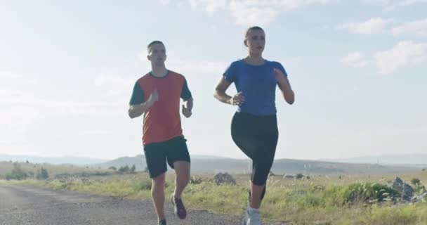 Rastreamento tiro em câmera lenta de casal esportivo correndo ao ar livre pela manhã, experiência de corrida de trilha na natureza. Conceito de estilo de vida saudável. — Vídeo de Stock