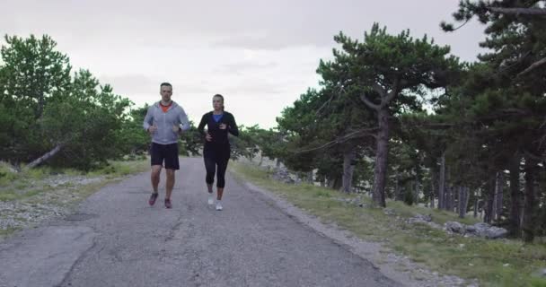 Sledování zpomaleného záběru sportovního páru jogging venku v dopoledních hodinách, stezka běží zkušenosti v přírodě. Zdravý životní styl koncept. — Stock video