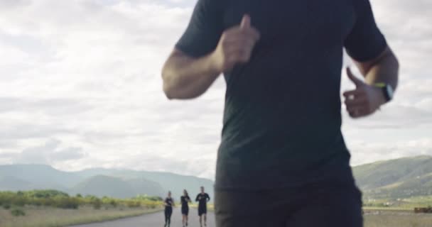 Grupo multiétnico de atletas corriendo juntos en una carretera panorámica del campo. Equipo diverso de corredores en el entrenamiento matutino. — Vídeos de Stock