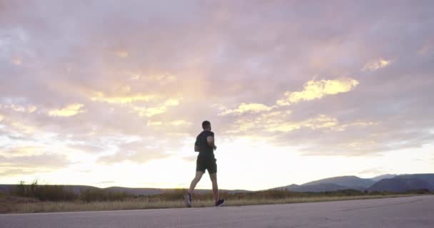 Man jogging on countryside road at sunset for health and wellness. — Stock videók