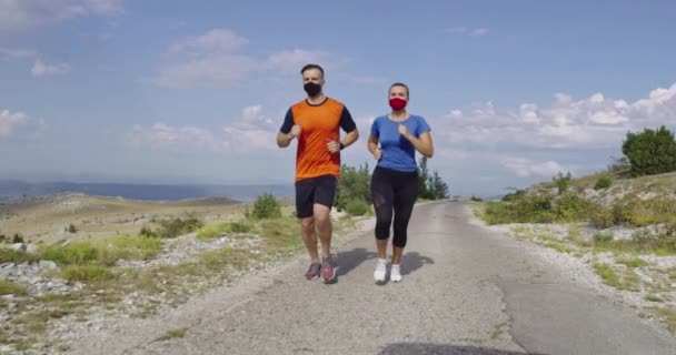 Mladý pár v lékařských maskách pobíhající po silnici během pandemie. Sport a koronavirus. Covid-19. — Stock video