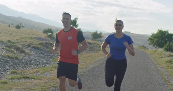 Tracking slow motion shot van sportief koppel joggen buiten in de ochtend, trail running ervaring in de natuur. Gezond levensstijl concept. — Stockvideo