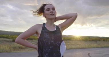 Woman takes a break from running at sunset