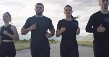 Multiethnic group of athletes running together on a panoramic road. Aerial drone view.