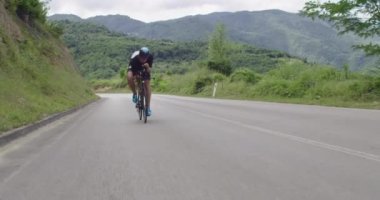Profesyonel yarış bisikleti süren triatlon sporcusu bir bisikletçi. Siyah spor giyim kuşam. 