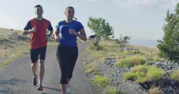 Rastreamento tiro em câmera lenta de casal esportivo correndo ao ar livre pela manhã, experiência de corrida de trilha na natureza. Conceito de estilo de vida saudável. — Vídeo de Stock