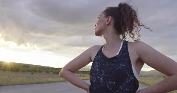 Woman takes a break from running at sunset — Stock Video