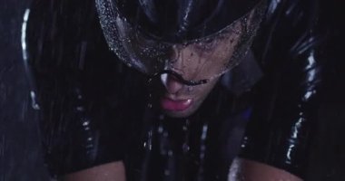Triatlon atleti, yağmurlu bir karanlıkta yoğun bir idmanda profesyonel bir yarış bisikletine biniyor. Yağmurlu bir gecede kötü hava koşullarında antrenman ya da yarışma. Ağır çekim. Merhaba kaliteli 4K görüntüler