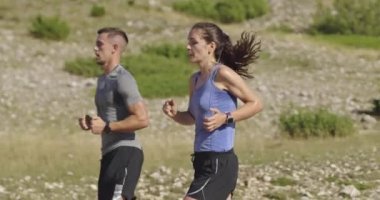 Sportif bir çift sabah dışarıda koşuyor, doğada iz sürme deneyimi var. Sağlıklı yaşam tarzı kavramı. Yüksek kaliteli görüntüler. Seçici odaklanma. Yavaş çekim takip ediliyor..