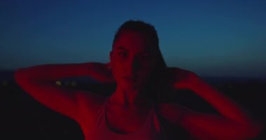 Şehir merkezinde gece gündüz egzersiz yaptıktan sonra dinlenen yorgun kadın sporcunun yavaş çekimde çekilmiş portresi. Yüksek kalite 4K görüntü. Seçici odak. 