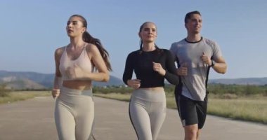 Panoramik bir kırsal yolda birlikte koşan çok ırklı bir grup sporcu. Çeşitli koşu takımları sabah antrenmanında. Yüksek kaliteli görüntüler. Ağır çekim takip ediliyor.. 