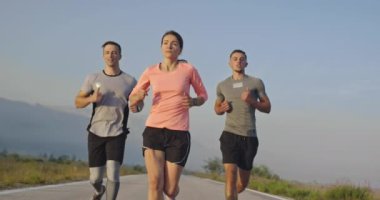 Panoramik bir kırsal yolda birlikte koşan çok ırklı bir grup sporcu. Çeşitli koşu takımları sabah antrenmanında. Yüksek kaliteli görüntüler. Ağır çekim takip ediliyor.. 