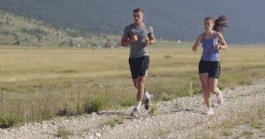Sportif bir çift sabah dışarıda koşuyor, doğada iz sürme deneyimi var. Sağlıklı yaşam tarzı kavramı. Yüksek kaliteli görüntüler. Seçici odaklanma. Yavaş çekim takip ediliyor..