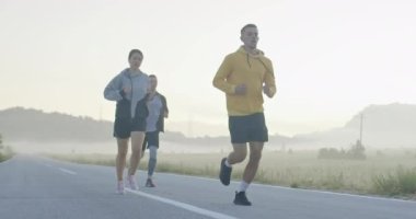 Panoramik bir kırsal yolda birlikte koşan çok ırklı bir grup sporcu. Çeşitli koşu takımları sabah antrenmanında. Yüksek kaliteli görüntüler. Ağır çekim takip ediliyor.. 