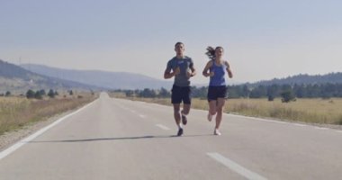 Sportif bir çift sabah dışarıda koşuyor, doğada iz sürme deneyimi var. Sağlıklı yaşam tarzı kavramı. Yüksek kaliteli görüntüler. Seçici odaklanma. Yavaş çekim takip ediliyor..