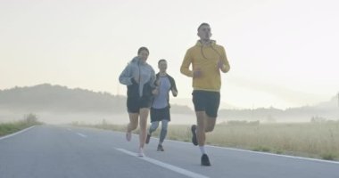 Panoramik bir kırsal yolda birlikte koşan çok ırklı bir grup sporcu. Çeşitli koşu takımları sabah antrenmanında. Yüksek kaliteli görüntüler. Ağır çekim takip ediliyor.. 