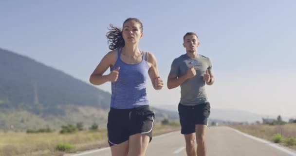 朝に屋外でスポーツカップルジョギングのスローモーションショットを追跡し、自然界でのトレイルランニング体験。健康的なライフスタイルのコンセプト. — ストック動画