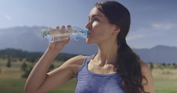飲料水を飲みながら激しいジョギング運動で休んでいる間に スポーティなトレイルランニング女性のスローモーションショット 顔に水を吹きかけて体を冷やす 高品質4K映像 選択的焦点 — ストック動画