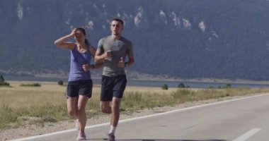 Sportif bir çift sabah dışarıda koşuyor, doğada iz sürme deneyimi var. Sağlıklı yaşam tarzı kavramı. Yüksek kaliteli görüntüler. Seçici odaklanma. Yavaş çekim takip ediliyor..