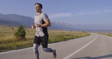 Panoramik bir kırsal yolda birlikte koşan çok ırklı bir grup sporcu. Çeşitli koşu takımları sabah antrenmanında. Yüksek kaliteli görüntüler. Ağır çekim takip ediliyor.. 