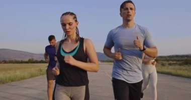 Panoramik bir kırsal yolda birlikte koşan çok ırklı bir grup sporcu. Çeşitli koşu takımları sabah antrenmanında. Yüksek kaliteli görüntüler. Ağır çekim takip ediliyor.. 