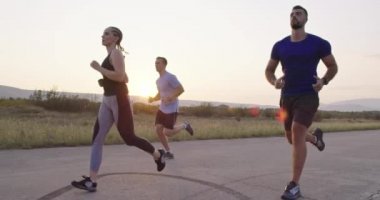 Panoramik bir kırsal yolda birlikte koşan çok ırklı bir grup sporcu. Çeşitli koşu takımları sabah antrenmanında. Yüksek kaliteli görüntüler. Yavaş çekim takip çekimi. Seçici odak. 