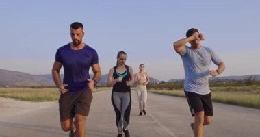 Panoramik bir kırsal yolda birlikte koşan çok ırklı bir grup sporcu. Çeşitli koşu takımları sabah antrenmanında. Yüksek kaliteli görüntüler. Ağır çekim takip ediliyor.. 