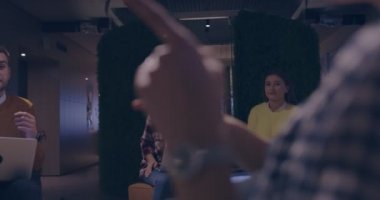 Modern bir açık alanda çalışan Müslüman bir kadın takıma bir sunum yapıyor. Orta Doğulu Arap iş kadını yaratıcı bir ofiste. Ekip toplantısında tekerlekli sandalyedeki engelli iş adamı 