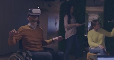 Modern açık uzay ofisinde çalışan engelli bir iş adamı sanal gerçeklik gözlüğü ve İHA simülasyonu kullanarak takım toplantısı yapıyor. Girişim işinde etkin takım çalışması.