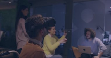 Modern açık uzay ofisinde çalışan engelli bir iş adamı sanal gerçeklik gözlüğü ve İHA simülasyonu kullanarak takım toplantısı yapıyor. Girişim işinde etkin takım çalışması.