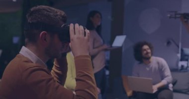 Tekerlekli sandalyedeki engelli işadamı, sanal gerçeklik gözlüğü ve insansız hava aracı simülasyonu kullanarak takım toplantısı için modern açık alan ofisinde çalışıyor.