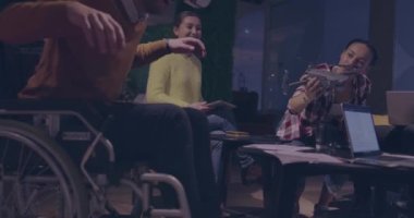 Tekerlekli sandalyedeki engelli işadamı, sanal gerçeklik gözlüğü ve insansız hava aracı simülasyonu kullanarak takım toplantısı için modern açık alan ofisinde çalışıyor.