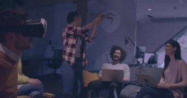 Tekerlekli sandalyedeki engelli işadamı, sanal gerçeklik gözlüğü ve insansız hava aracı simülasyonu kullanarak takım toplantısı için modern açık alan ofisinde çalışıyor.