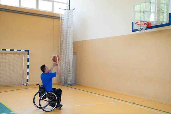 Una guerra inválida en una silla de ruedas entrena con una pelota en un club de baloncesto en el entrenamiento con equipos deportivos profesionales para discapacitados. el concepto de deporte para las personas con discapacidad — Foto de Stock