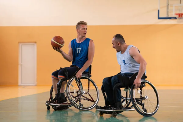 Veteranos de guerra deficientes em cadeiras de rodas com equipamento profissional jogar jogo de basquete no hall.the conceito de esportes com deficiência — Fotografia de Stock