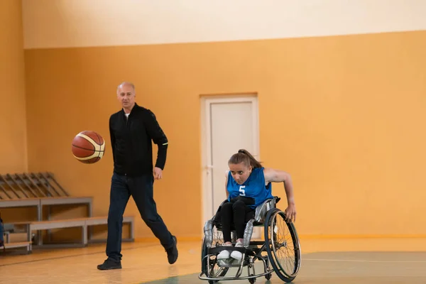 Ein Sport-Basketballtrainer erklärt einer behinderten Frau im Rollstuhl, in welcher Position sie während eines Spiels spielen soll — Stockfoto